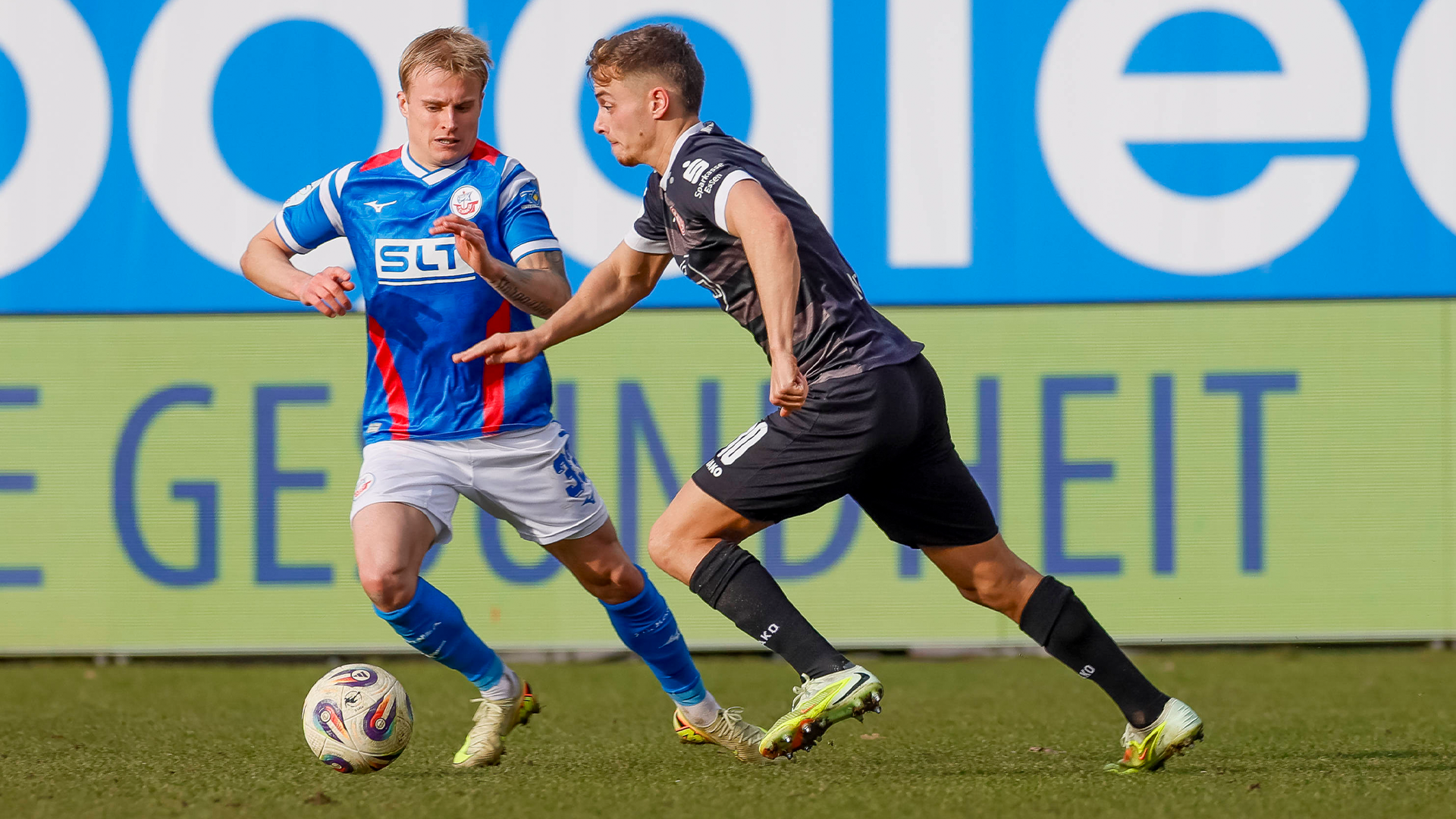 Ein Fußballspieler von RW Essen und ein Spieler vom TSV 1860 München kämpfen um den Ball